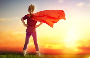 Little child girl plays superhero. Child on the background of sunset sky. Girl power concept